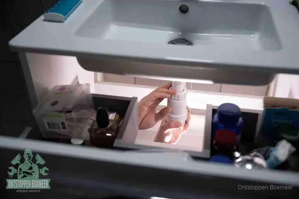 Een pompfles met zeep boven een wastafel, de heet water en afwasmiddel-methode om een vetprop in de afvoer los te maken in Boxmeer