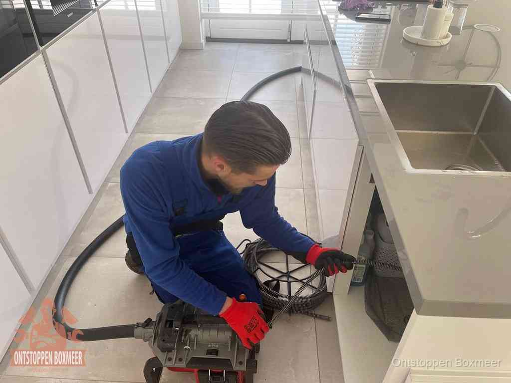 Een monteur ontstopt de keukenafvoer onder de spoelbak met een elektrische veermachine in Boxmeer Een monteur ontstopt de keukenafvoer onder de spoelbak met een elektrische veermachine in Boxmeer
