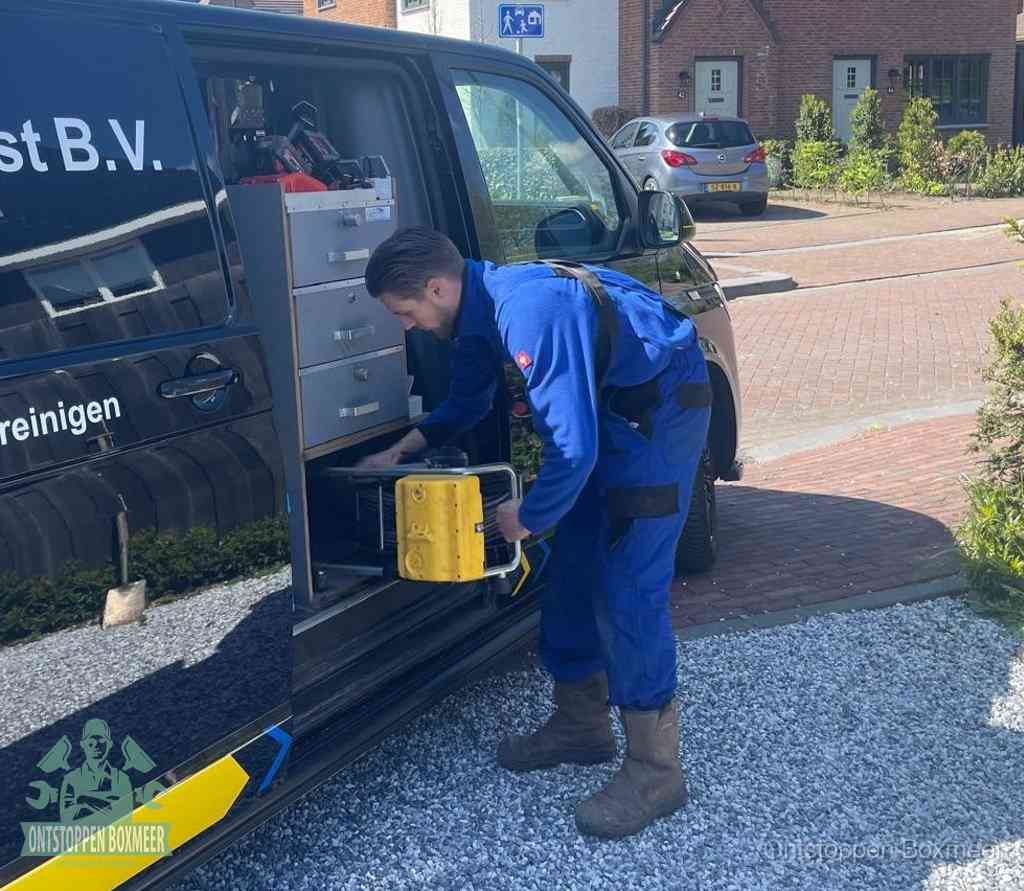 Een monteur pakt buiten op de oprit gereedschap uit de bedrijfsbus, het moment om een professional in te schakelen voor een verstopte afvoer in Boxmeer