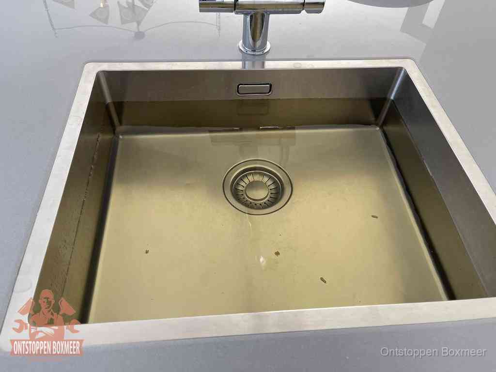 Stilstaand water in een rvs spoelbak dat niet wegloopt, een duidelijk signaal van een gootsteenverstopping in Boxmeer