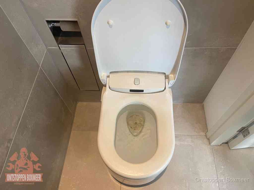 Een wit hangtoilet waarin een prop wc-papier op het water blijft drijven, een duidelijk signaal van een verstopte wc in Boxmeer