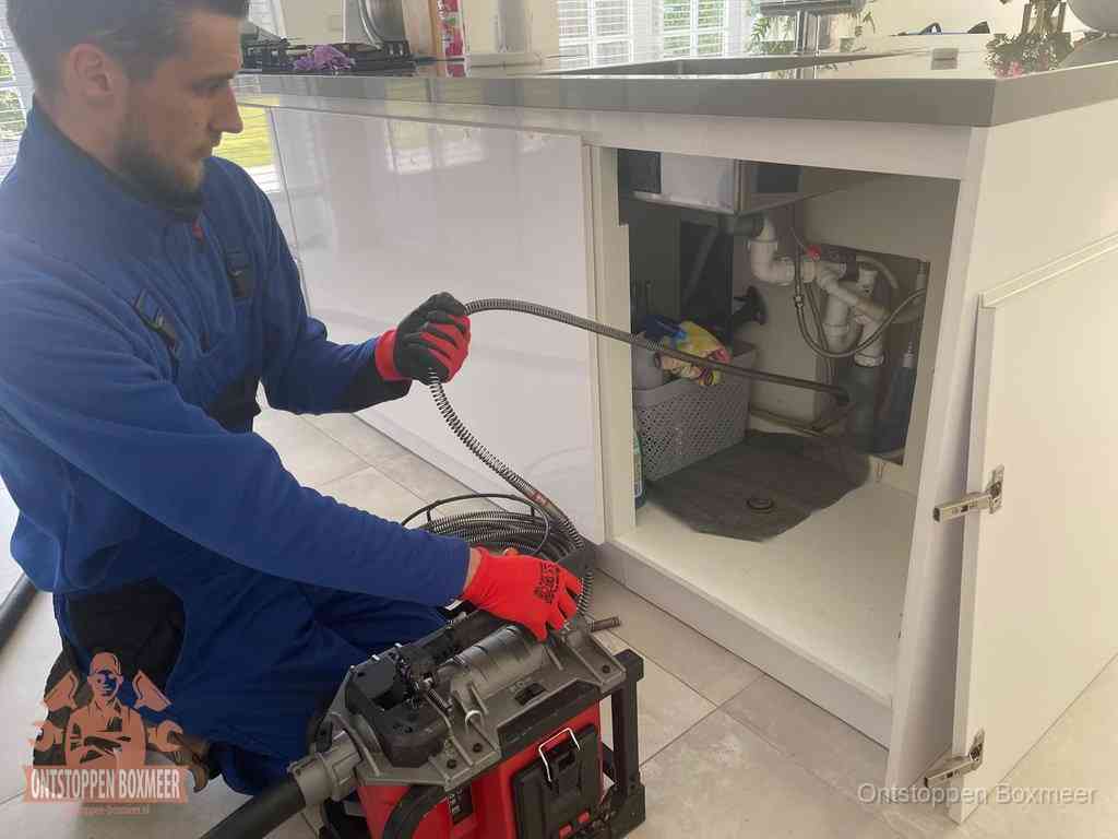 Een monteur reinigt de keukenafvoer grondig met een veermachine om terugkerende gootsteenverstoppingen te voorkomen in Boxmeer Een monteur reinigt de keukenafvoer grondig met een veermachine om terugkerende gootsteenverstoppingen te voorkomen in Boxmeer
