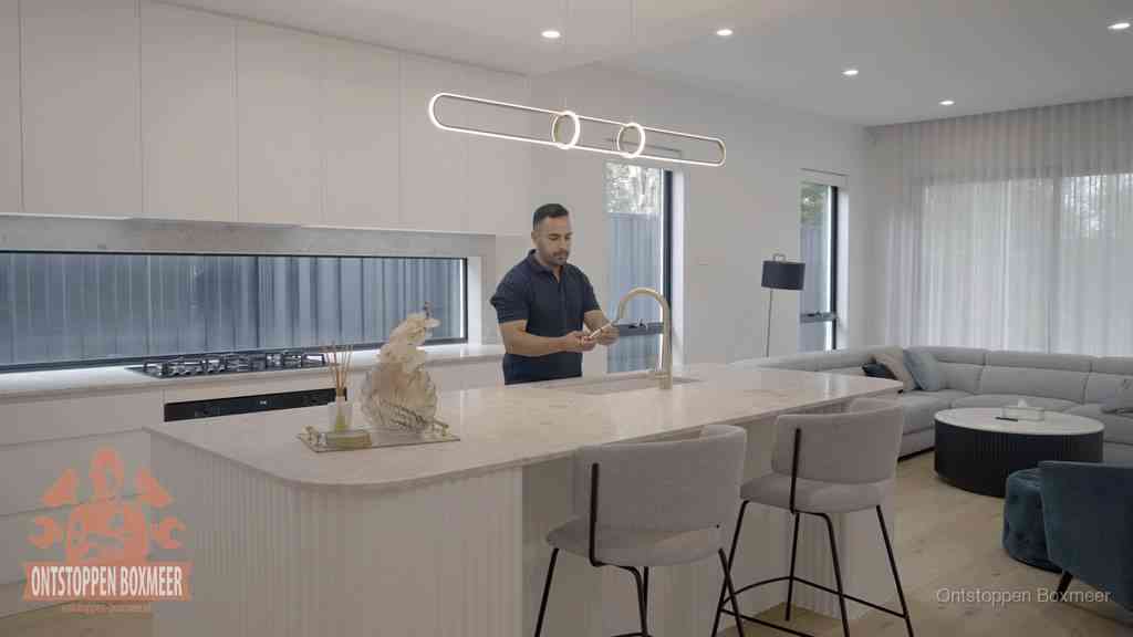 Een bewoner bij de keukenspoelbak die zelf aan de slag gaat met een verstopte gootsteen in Boxmeer Een bewoner bij de keukenspoelbak die zelf aan de slag gaat met een verstopte gootsteen in Boxmeer